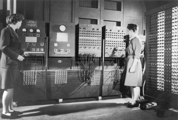 Women were ENIAC’s first programmers, but their role was obscured for decades. Here two women stand infront of one ENIAC, one of the computer systems. The computer is huge with switches and lights