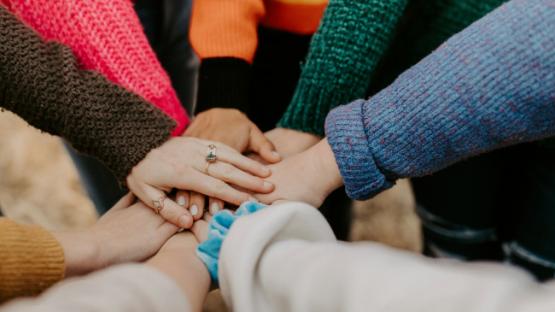 People in colourful sweaters holding hands