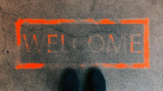 Feet standing in front of faded orange 'welcome' message on ground