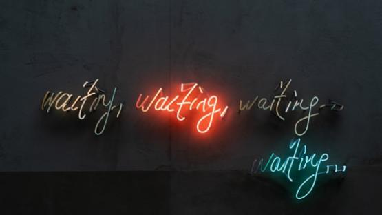 Four neon light signs saying repeatedly the word 'waiting'