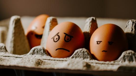 Two eggs in a crate with faces drawn on them, one clearly bad and other mildly embarassed