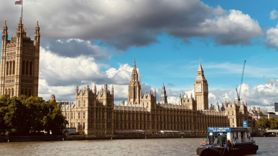 UK Westminister Abbey on a sunny day, with a boat on the thames in the foreground
