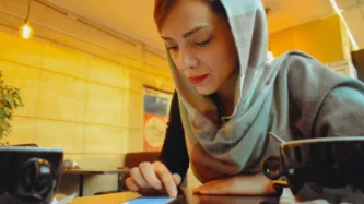 A person at a table in a cafe looking at a phone