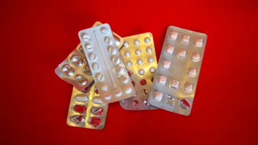 Generic silver blister pill packets on a red background