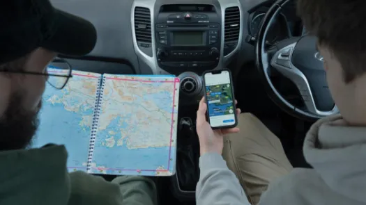 Two people looking at a map and Google Maps in a car